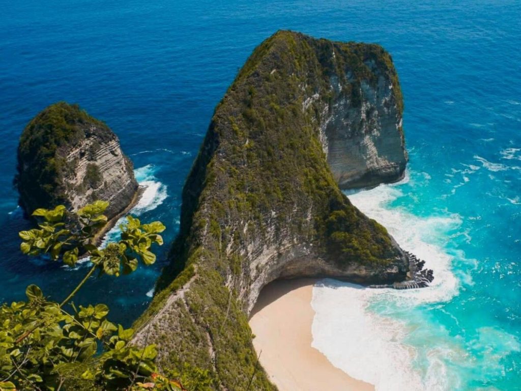L'iconica spiaggia di Kelingking a Nusa Penida, Indonesia, famosa per la sua scogliera a forma di testa di T-Rex che si affaccia su un mare blu intenso e una caletta di sabbia bianca
