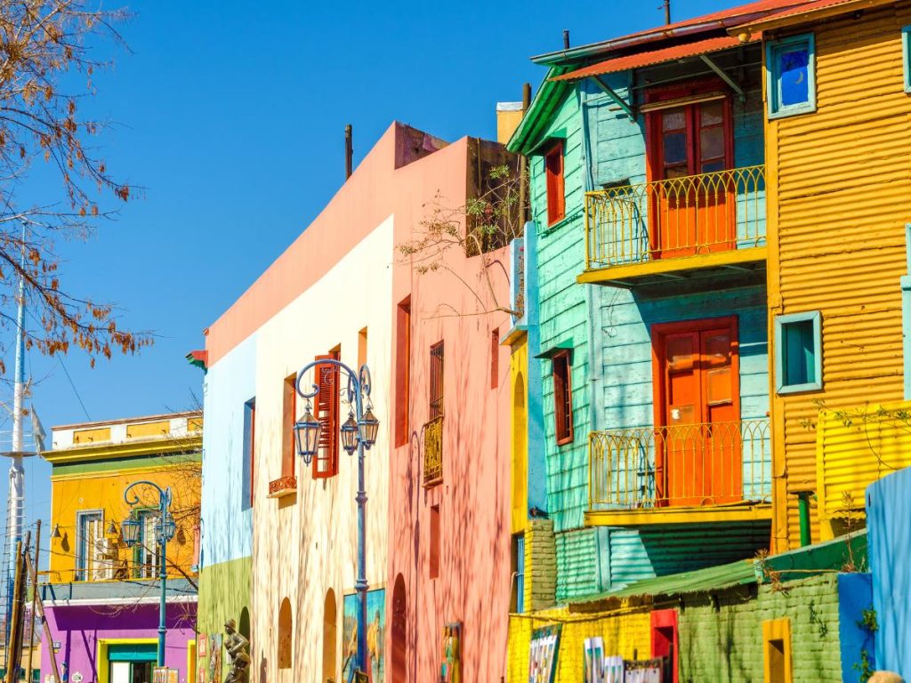 Facciate di case storiche dai colori vivaci e accesi lungo la celebre via Caminito nel quartiere La Boca a Buenos Aires, sotto un cielo blu limpidissimo.