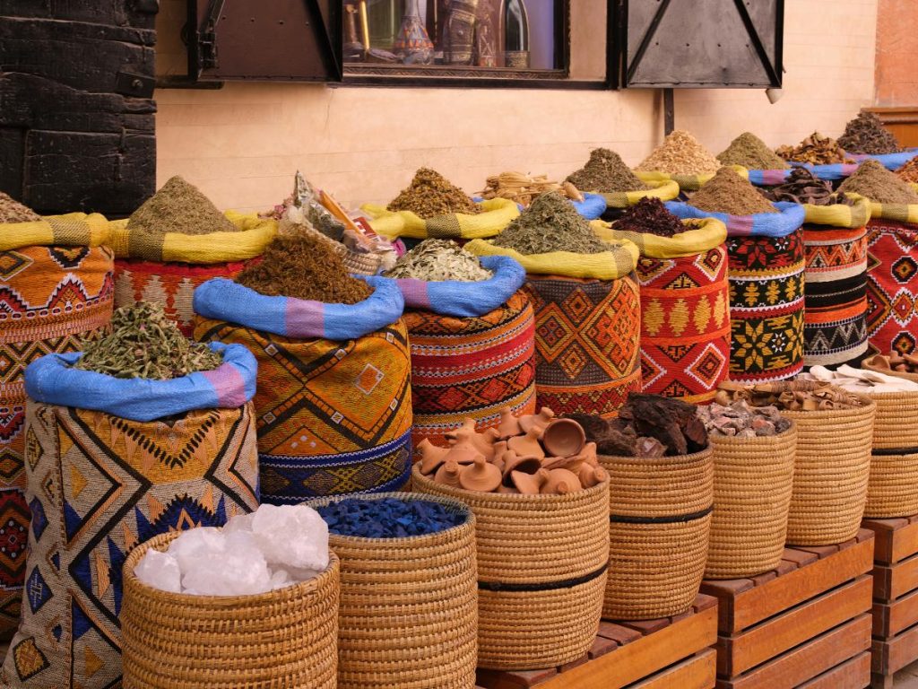Sacchi di stoffa colorata e cestini di paglia colmi di spezie, erbe essiccate e pigmenti in un mercato tradizionale che si visita per la prima volta in Marocco.