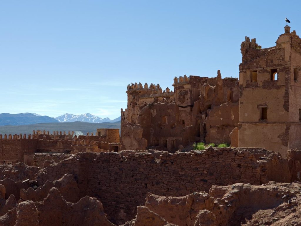 Rovine di una kasbah in pietra e fango in Marocco con sullo sfondo le cime innevate della catena montuosa dell'Atlante.