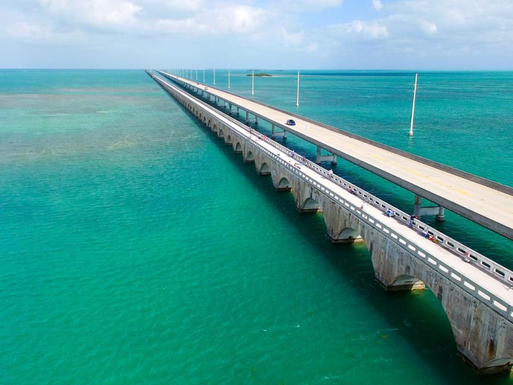 Veduta aerea del Seven Mile Bridge a Key West, in Florida, sospeso su un mare cristallino dalle sfumature turchesi e verde acqua sotto un cielo sereno.