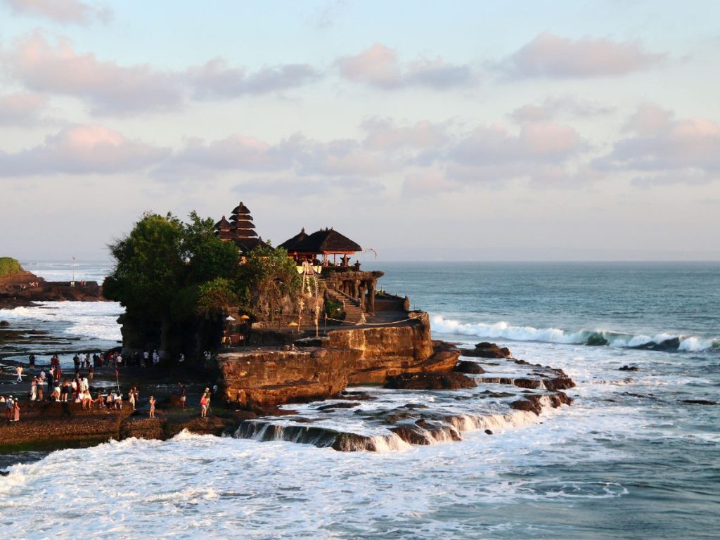 Il tempio induista Tanah Lot a Bali arroccato su una formazione rocciosa circondata dalle onde dell'oceano, da vedere durante un viaggio originale in Indonesia.