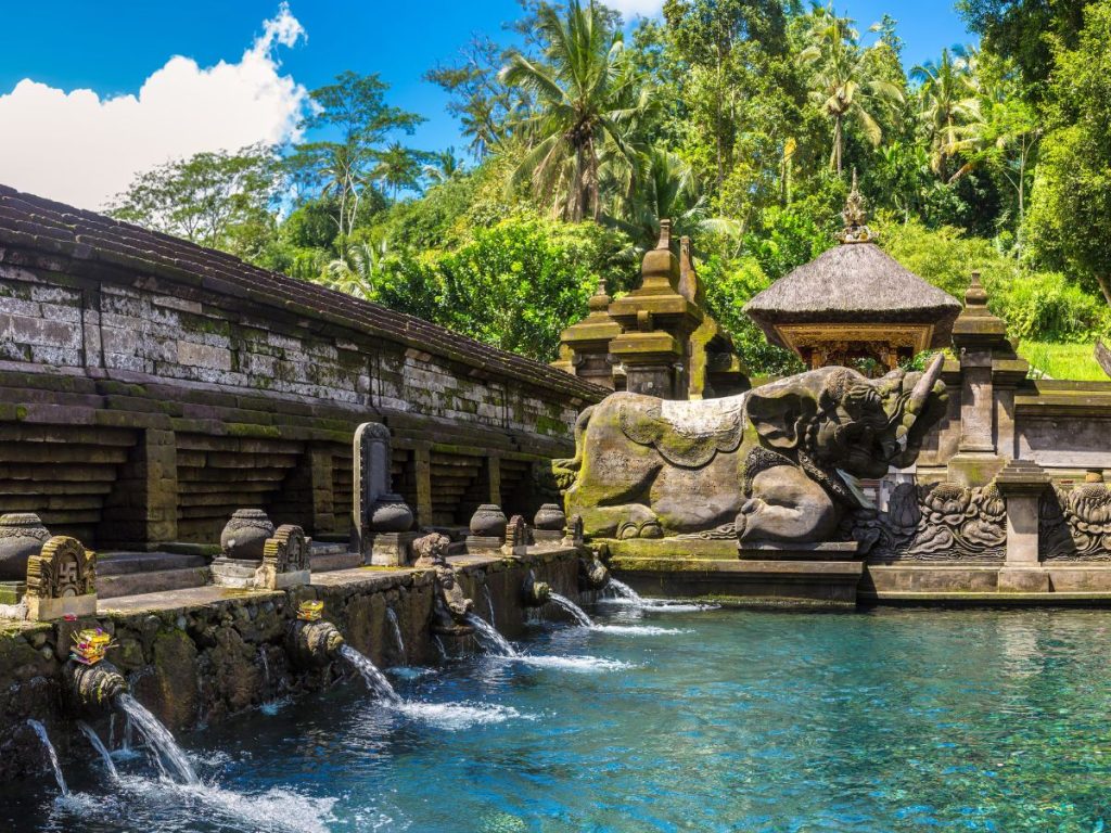 Vasca di purificazione del tempio di Tirta Empul a Bali con sorgenti sacre e sculture tradizionali in pietra.