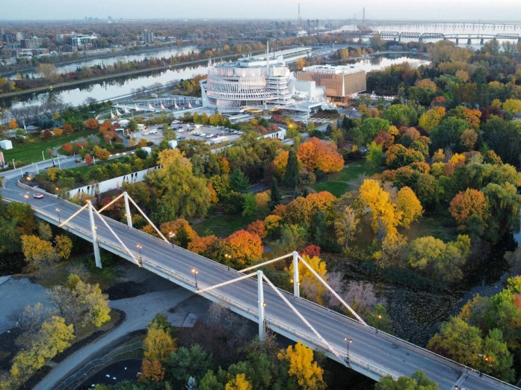 Veduta aerea autunnale di Montréal con un ponte stradale in primo piano, alberi dai colori vivaci e lo sfarzoso edificio del Casinò sullo sfondo.