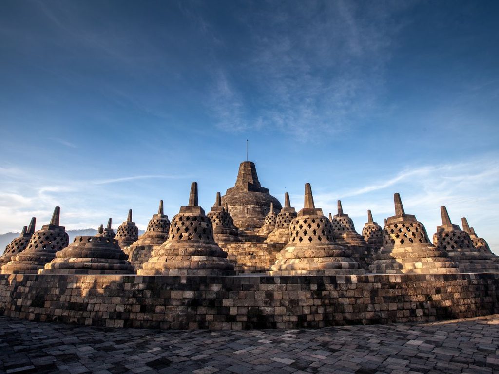 Le antiche stupa in pietra del tempio buddista di Borobudur a Giava sotto un cielo azzurro.