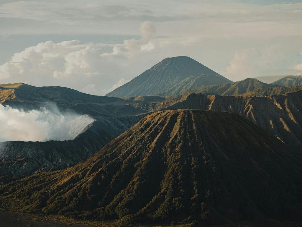 Paesaggio vulcanico dell'isola di Giava con il cono vulcanico del Monte Bromo e fumo in risalita dai crateri.
