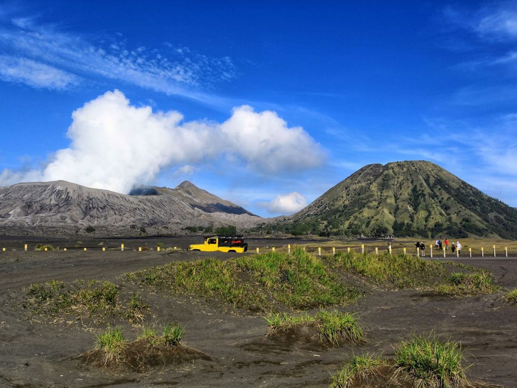 Fuoristrada giallo nella pianura di sabbia vulcanica ai piedi del Monte Bromo e del vulcano Batok a Giava.